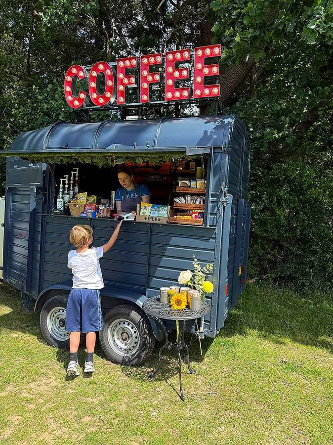 A young customer paying by card at the hatch of the coffee van