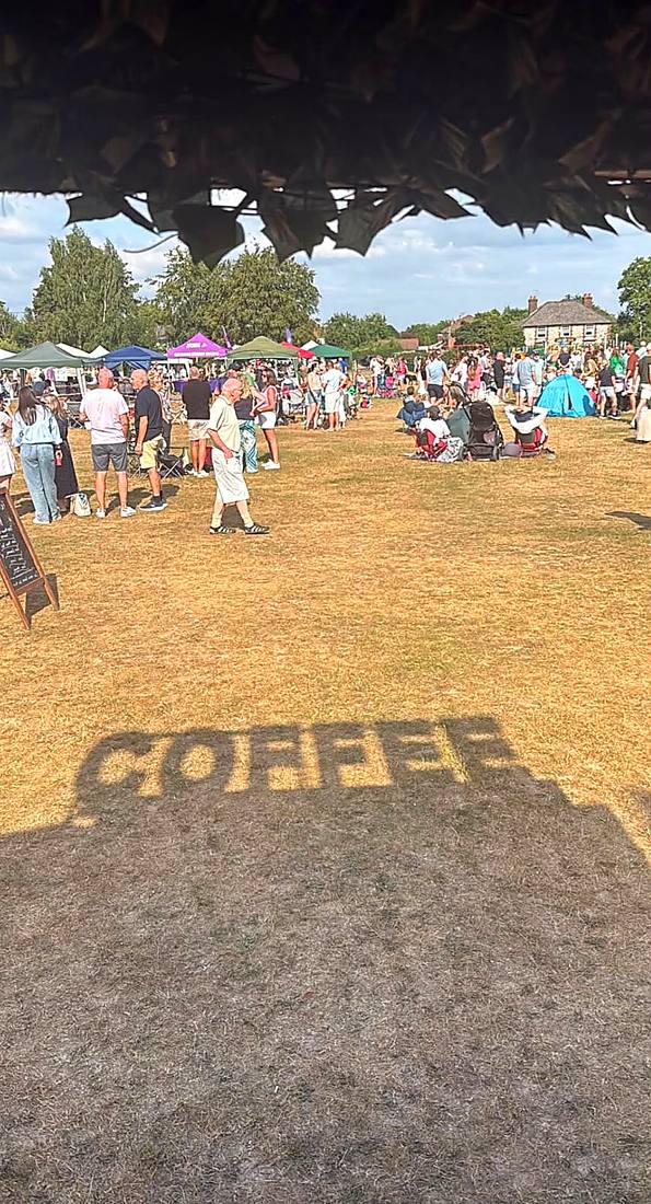 The shadow of the van's COFFEE sign cast across the grass at a busy summer fete