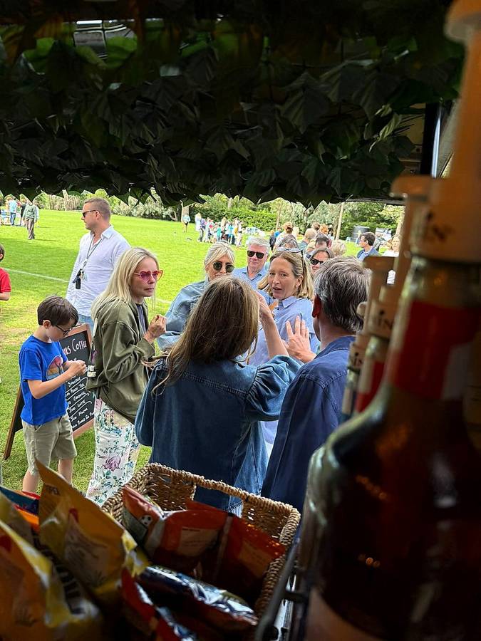 A crowd of guests gathered around the coffee van at a summer event