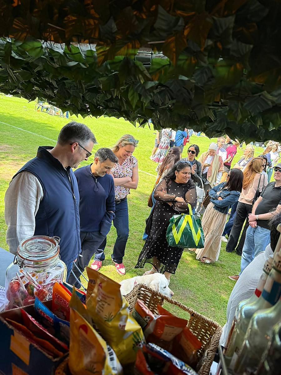 Guests waiting at the hatch on a village green, with a dog looking on