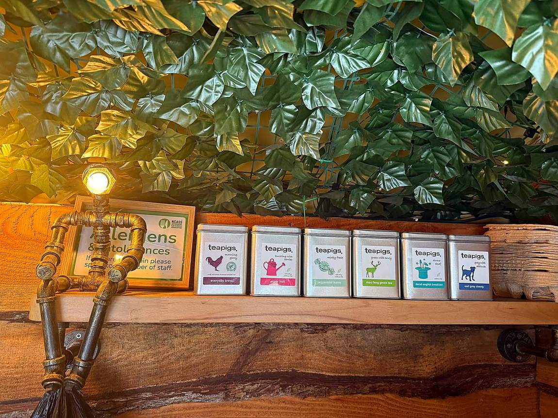 Teapigs tea tins on a timber shelf under warm bulbs inside the van