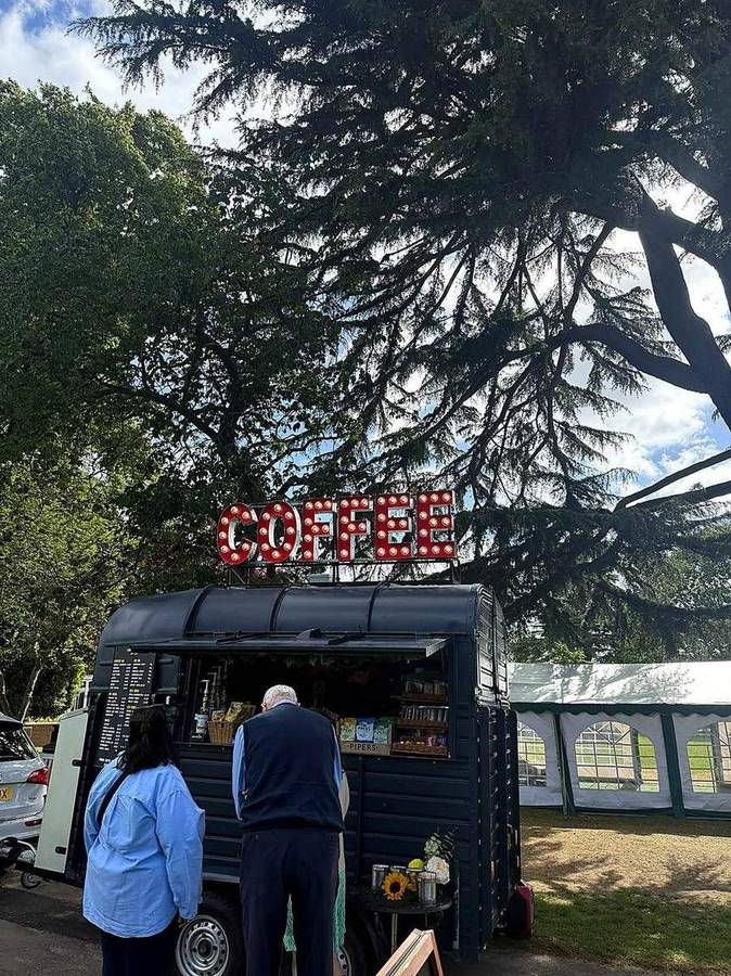 The coffee van beside an event marquee with guests ordering at the hatch